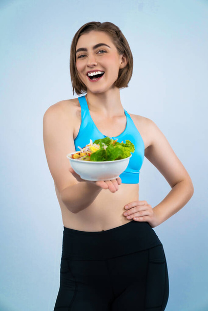 Vücut uzunluğunun tamamı atletik ve sportif, sağlıklı vejetaryen yiyeceklerle izole edilmiş arka planda duran genç bir bayanı çekiyor. Vejetaryen yaşam tarzından sağlıklı aktif ve vücut bakımı. - Fotoğraf, Görsel