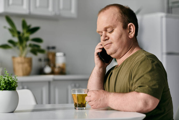 Un hombre con inclusividad se sienta en su mesa de la cocina, tomando un descanso de su día. - Foto, imagen