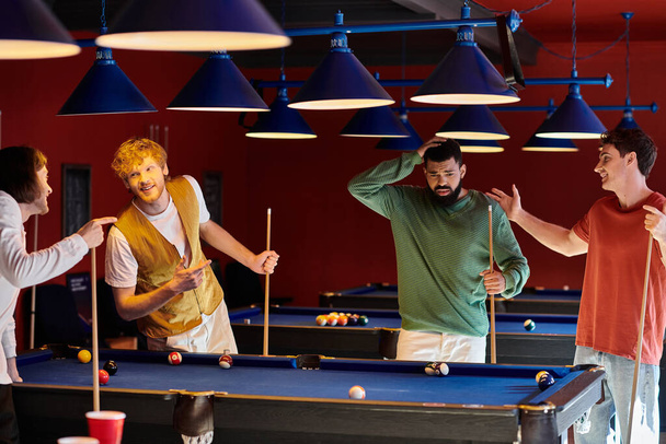 Friends are gathered around a pool table, laughing and enjoying a casual game of billiards. - Photo, Image