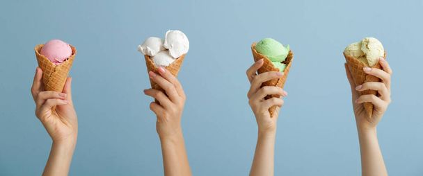 Mãos com diferentes sorvetes doces no fundo azul claro - Foto, Imagem