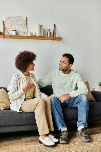 アフリカ系アメリカ人のカップルが自宅のソファーに座り,手話でコミュニケーションをとる. - 写真・画像