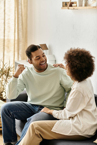 Ein afroamerikanisches Paar kommuniziert mit Gebärdensprache, während es zu Hause auf einer Couch sitzt. - Foto, Bild