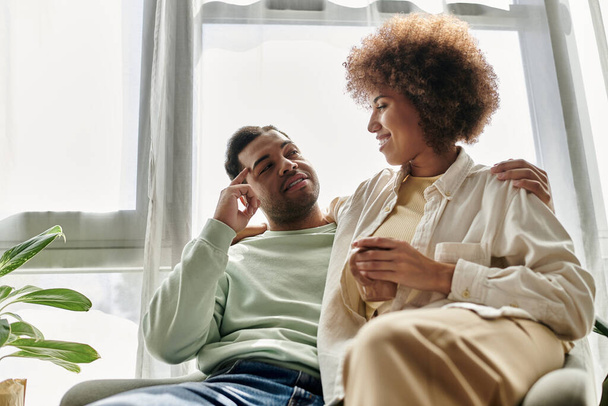 Una pareja afroamericana usa el lenguaje de señas para comunicarse entre sí en un entorno hogareño. - Foto, imagen