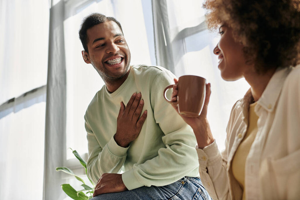 Szczęśliwa para Afroamerykanów używa języka migowego do porozumiewania się ze sobą podczas siedzenia w domu. - Zdjęcie, obraz