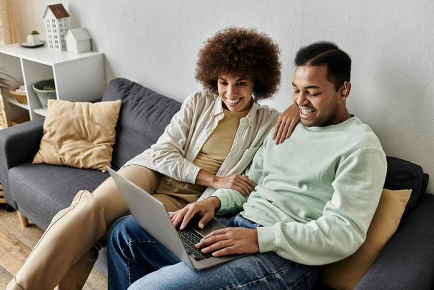 Attraente donna afroamericana seduta vicino al marito con apparecchi acustici e guardando il computer portatile. - Foto, immagini