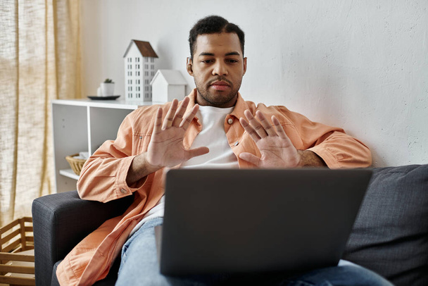 Um homem assina para laptop enquanto está sentado em um sofá. - Foto, Imagem