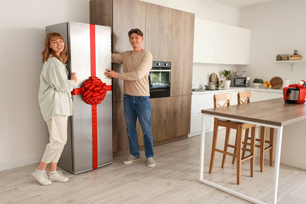 Jeune couple avec réfrigérateur cadeau dans la cuisine - Photo, image