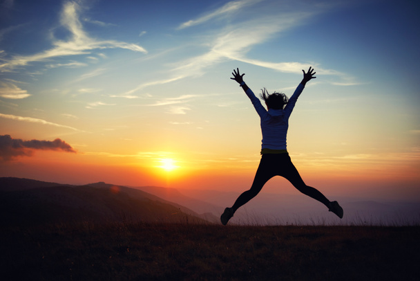 молода жінка стрибає на заході сонця
 - Фото, зображення