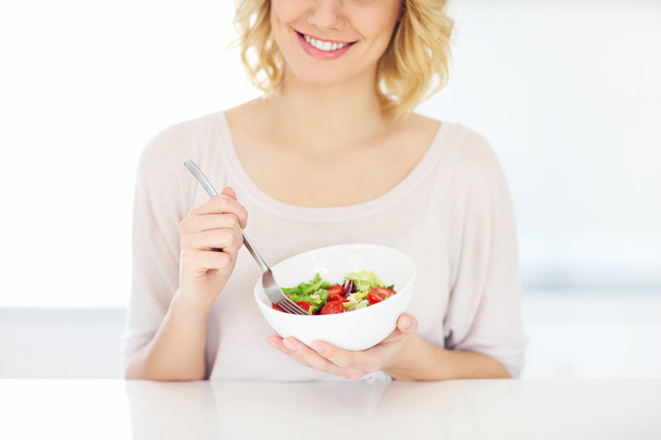 νεαρή γυναίκα τρώει σαλάτα στην κουζίνα - Φωτογραφία, εικόνα