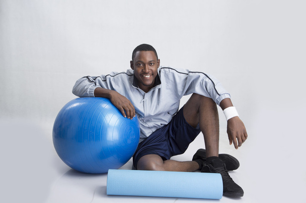 jeune sportif assis avec ballon et tapis
 - Photo, image