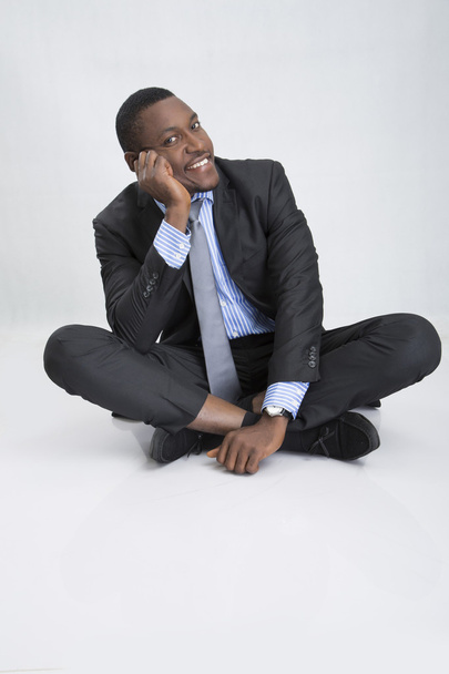 Молодой бизнесмен сидит на полу и улыбается
 - Фото, изображение