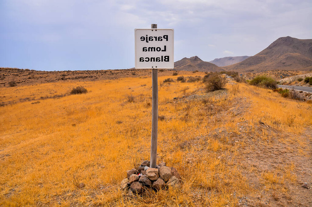 Un segnale nel deserto avverte di una zona pericolosa. Il segno è in lingua straniera, e il deserto è arido e arido - Foto, immagini