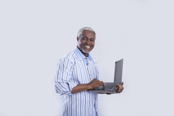 Мужчина в возрасте с ноутбуком на сером
 - Фото, изображение