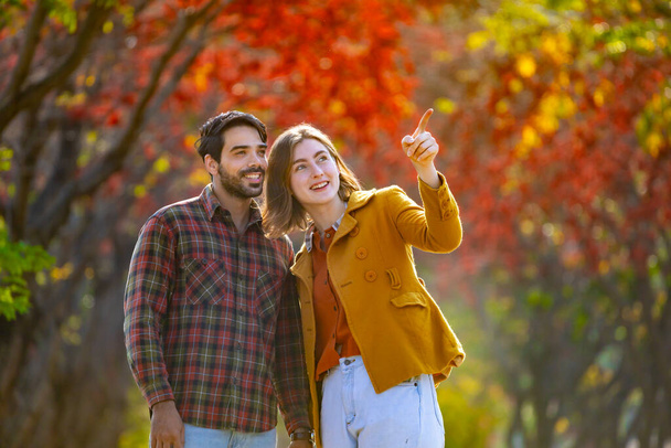 Happy caucasian couple walking together in public park during autumn with maple and beech tree for fall color travel destination and family happiness - Photo, Image
