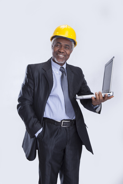 éves üzletember, a sárga bukósisak és laptop - Fotó, kép