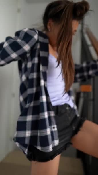 A young woman in a plaid shirt dances with joy in her room, expressing freedom and happiness in her private space - Filmmaterial, Video