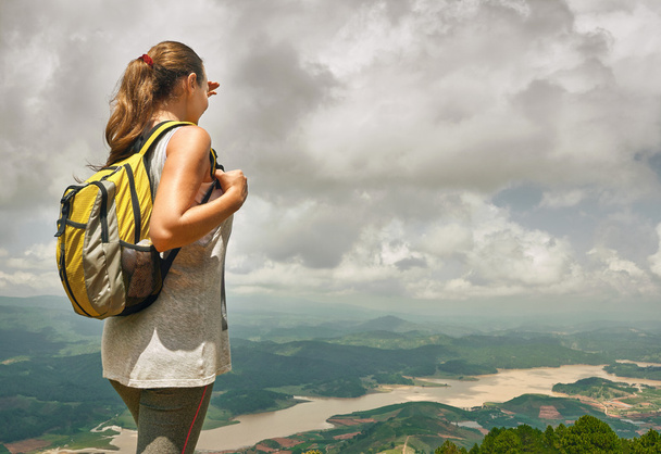 Молода жінка ходить з рюкзаком, стоячи на вершині гори
  - Фото, зображення
