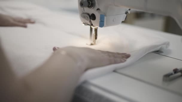 Mãos operando uma máquina de costura, unindo tecido com precisão. Processo de fabrico de têxteis em foco. - Filmagem, Vídeo
