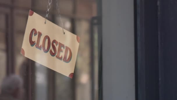 Cartel cerrado colgado en una puerta de cristal, indicando que la tienda o negocio no está operativo. - Imágenes, Vídeo