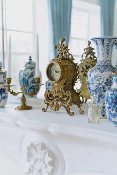 luxuriöse Innenausstattung. Vintage-Uhr und antike Vasen auf dem Kamin. Königshaus.  - Foto, Bild