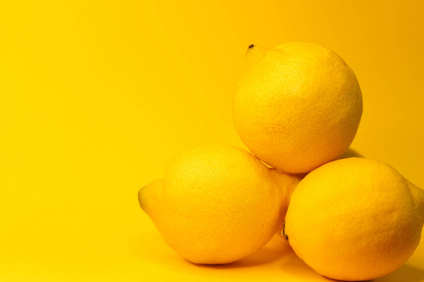 Limones amarillos sobre fondo amarillo, espacio para copiar - Foto, imagen