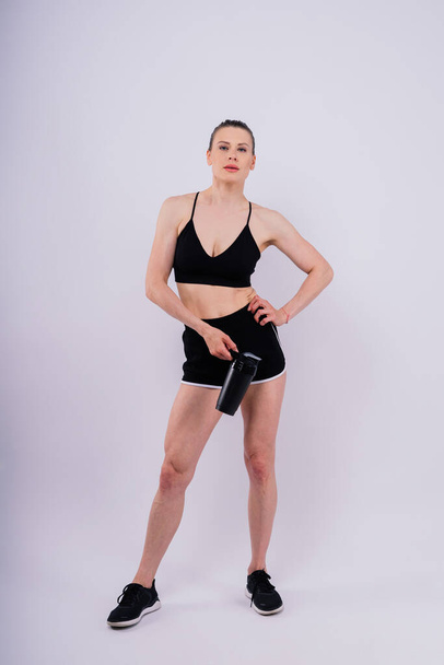 Αθλητικό γυναικείο πόσιμο νερό μετά την προπόνηση. Φωτογραφία μιας γυμνάστριας. Υγιής τρόπος ζωής - Φωτογραφία, εικόνα