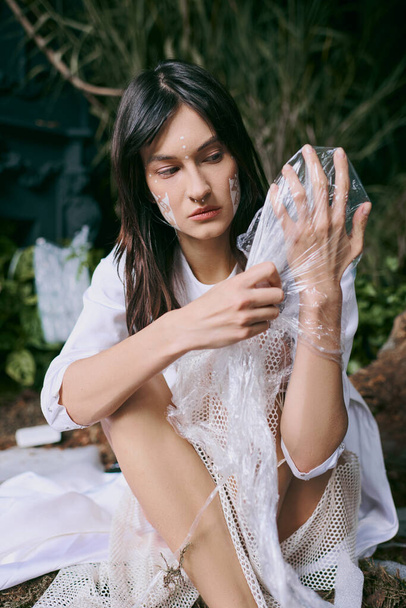 Жінка позує в болоті, наповненому пластиком, демонструючи вплив забруднень. - Фото, зображення
