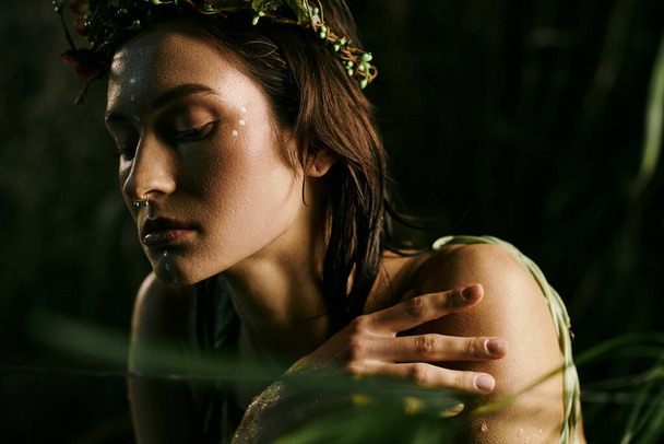 Kobieta z koroną kwiatową pozuje w cieniu bagna, otoczona bujną zielenią. - Zdjęcie, obraz