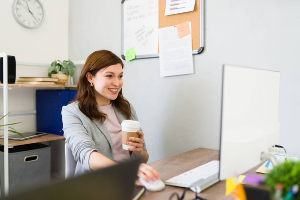 Mujer joven con una sonrisa, sosteniendo el café en un entorno moderno de la oficina de inicio, ilustrando la cultura contemporánea del trabajo empresarial - Foto, Imagen