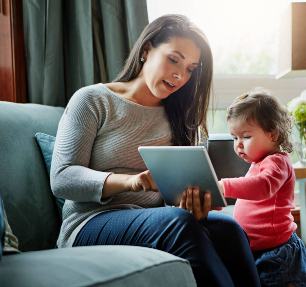 Koulutus, äiti ja lapsi tabletin kanssa olohuoneessa yhdessä internet-yhteyden ja kehityksen kotona. Nainen, lapsi tai tytär tech sohvalla verkossa oppimiseen ja opiskeluun rakkaudella. - Valokuva, kuva