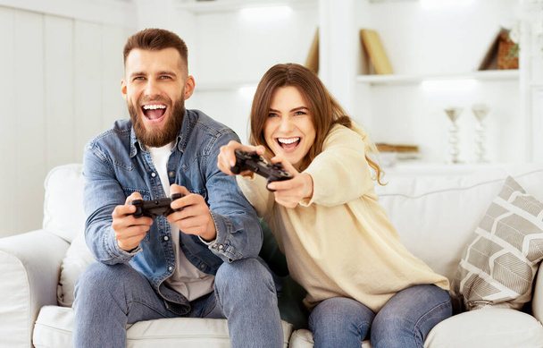 Fans van Xbox. Gek paar genieten van het spelen van video game op PlayStation, rusten thuis - Foto, afbeelding