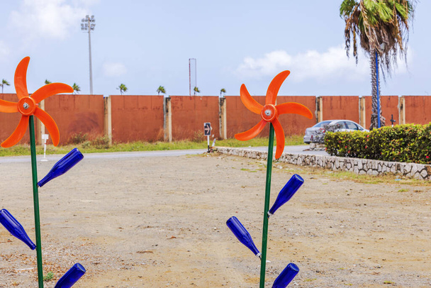 Beautiful view of colorful windmill decorations with blue bottles and orange blades in an outdoor setting against a clear sky. Curacao. - Photo, Image
