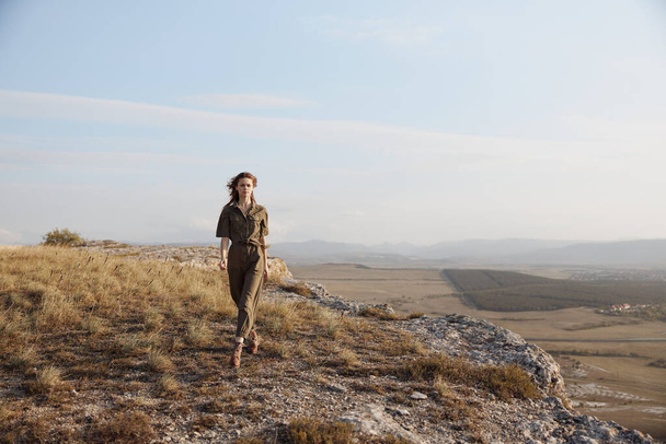Женщина, стоящая на вершине холма с видом на долину внизу с захватывающим видом на природу красоты - Фото, изображение