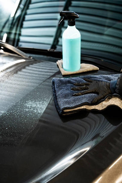 Applying quick detailer, spray and wiping to make clean and shine car surface. Polishing car body using microfiber cloth. Professional car valeting - Photo, Image