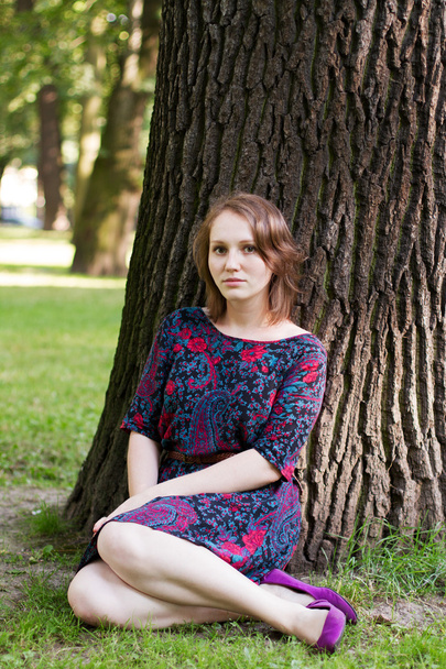 young woman sitting under a tree  - Foto, Bild