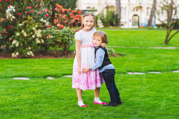 Két aranyos gyerekek játszani a parkban, party ruhában, szabadtéri portréja - Fotó, kép