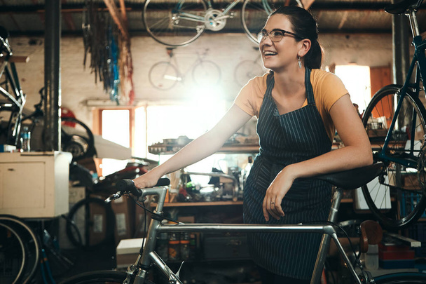 Kadın, bisiklet dükkânı ve bakım işleri, ulaşım hizmeti. Bisiklet, tamirci ve kadın girişimci atölyede fikir sahibi, sürdürülebilir iş ve mutluluk için düşünceli. - Fotoğraf, Görsel