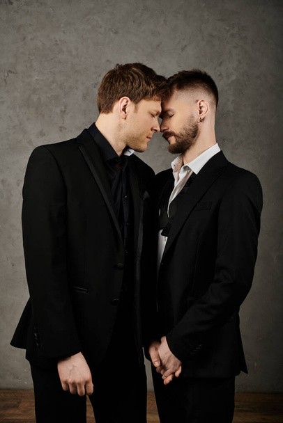 Twee mannen in elegante pakken omhelzen elkaar, hun voorhoofd raakt elkaar in een gebaar van genegenheid en intimiteit.. - Foto, afbeelding