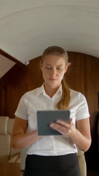 Бизнес-леди в частном самолете серфинг Интернет на планшетном компьютере. Концепция путешествий состоятельных и богатых бизнесменов. Работает в небольших частных бизнес-самолетов. Вертикальный выстрел. - Кадры, видео