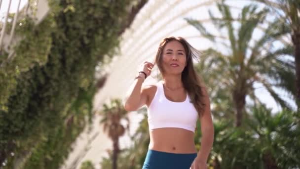 スポーツウェアのアジア東洋の大人の女性ジョギングは,トレーニングの朝のトレッドミル都市ハイテクの背景を実行する前に筋肉や関節の暖かいアップを行います. 大人のための都市の健康的なライフスタイル - 映像、動画