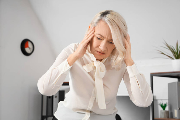 Volwassen zakenvrouw ervaart menopauze in het kantoor - Foto, afbeelding