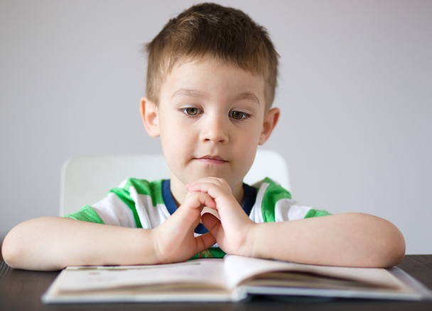 Little boy is reading a book - Фото, изображение
