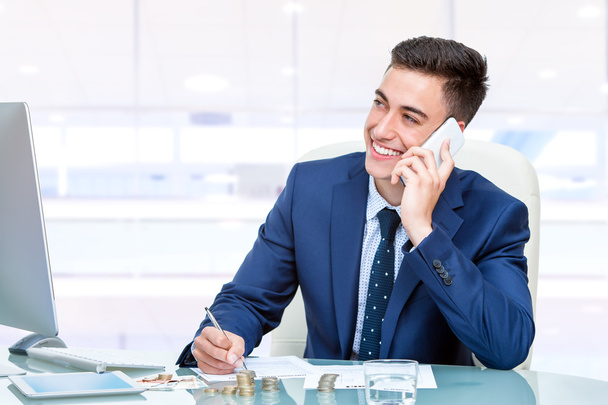 Бизнесмен разговаривает по телефону в офисе - Фото, изображение