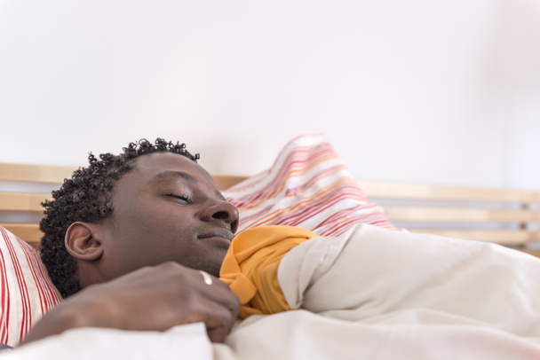 Peaceful african american man sleeping in bed - Foto, afbeelding