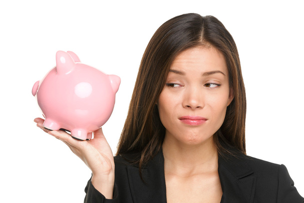 Woman looking displeased at piggy bank - Foto, Bild