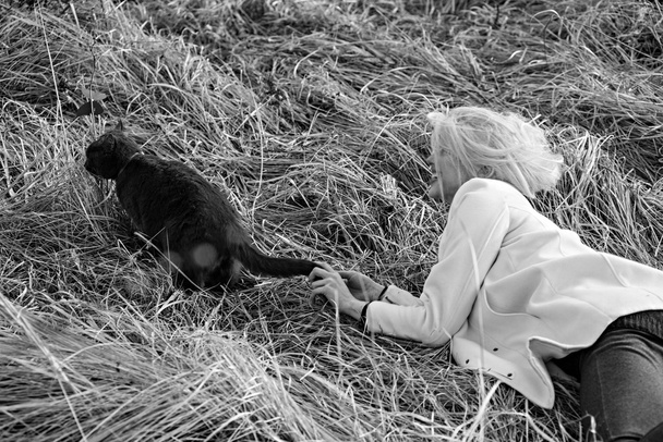 Fiatal lány játszik egy cica a fűben. - Fotó, kép
