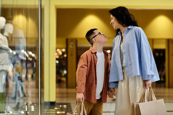 Matka i jej syn z zespołem Downa przechodzą przez centrum handlowe, ciesząc się dniem spędzonym razem. - Zdjęcie, obraz