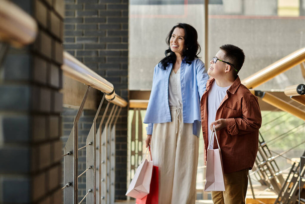 Eine Mutter und ihr Sohn mit Down-Syndrom spazieren durch ein Einkaufszentrum und genießen einen gemeinsamen Tag. - Foto, Bild
