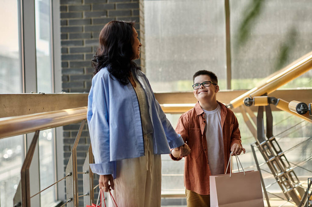 Una madre y su hijo con síndrome de Down están de compras juntos en el centro comercial, disfrutando de la compañía de los demás. - Foto, Imagen