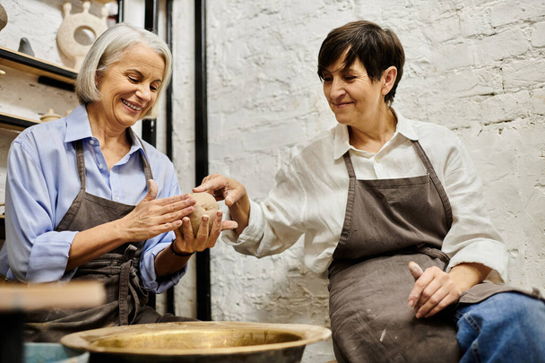 Due donne in abbigliamento accogliente stanno lavorando con argilla in uno studio d'arte. - Foto, immagini